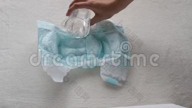 女孩把杯子里的水倒进婴儿尿布，擦拭餐巾纸、特写、尿布和水